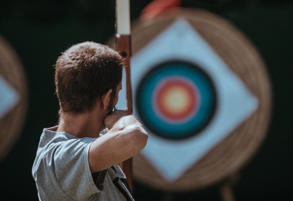 Man with a bow aiming at an archery target