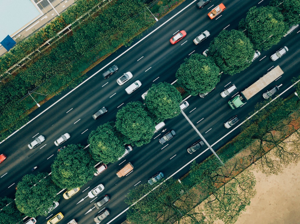 arial view of cars driving along a tree-lined road