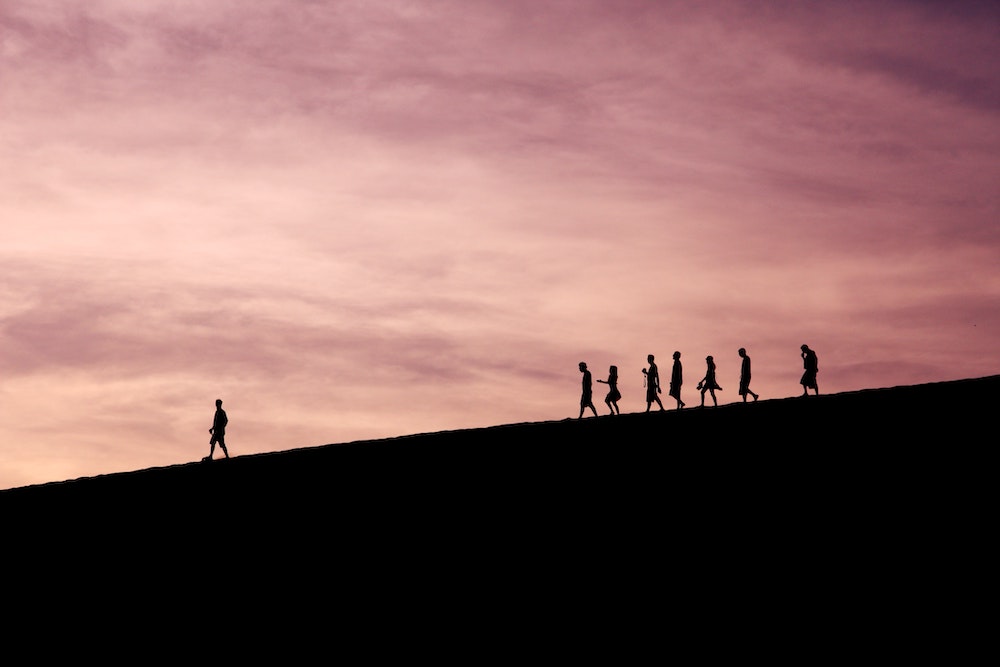 silhouettes of people walking down a hill